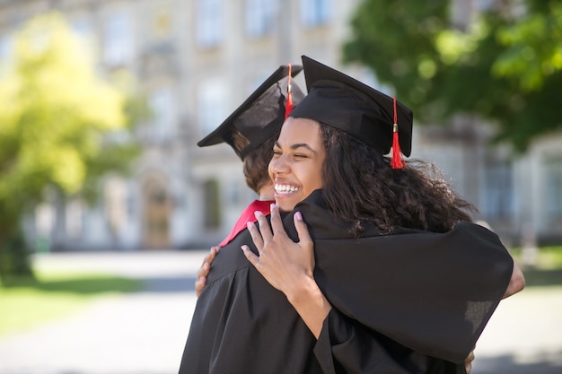 Happy graduates. friends hugging each other after graduation\
and feeling happy