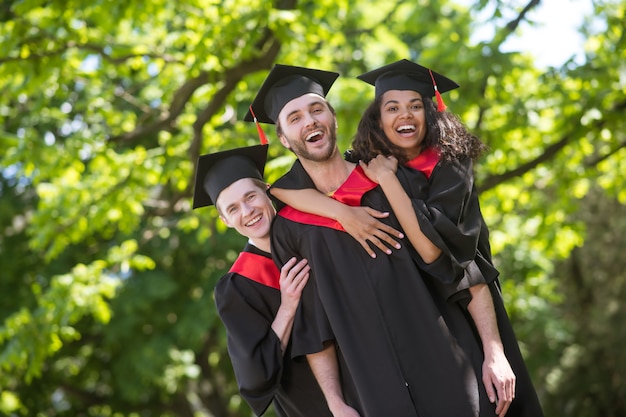 Happy graduates. Group of graduates standing in park and feeling amazing