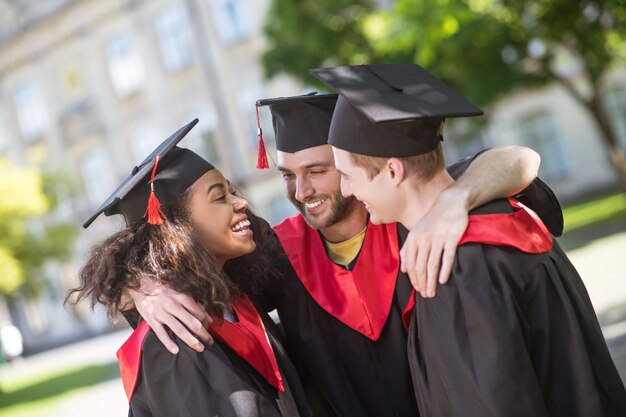 Happy graduates. three graduates hugging and discussing their graduation