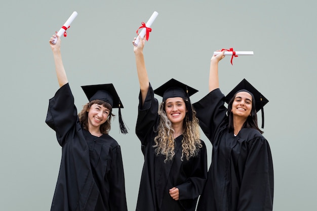 Happy graduating students celebrating with diplomas in the\
air