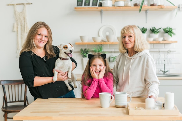 Happy granddaughter and grandmother and daughter having fun with jack russell terrier dog. Grandma hugs grandchild at home. Relationship, family and three generation concept.