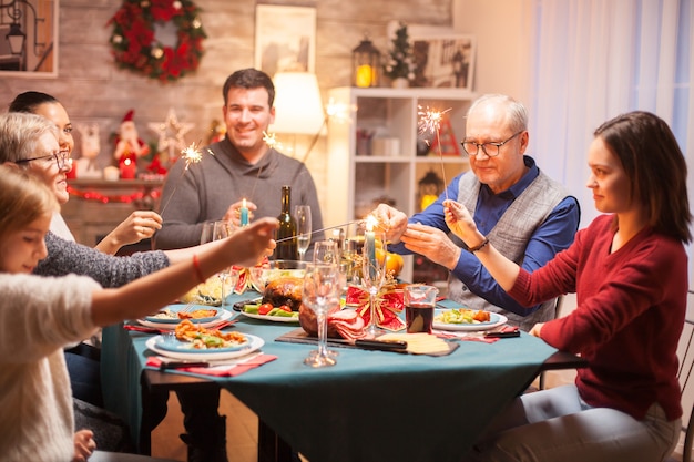 クリスマスの家族の夕食で手花火で遊んで幸せな孫娘。