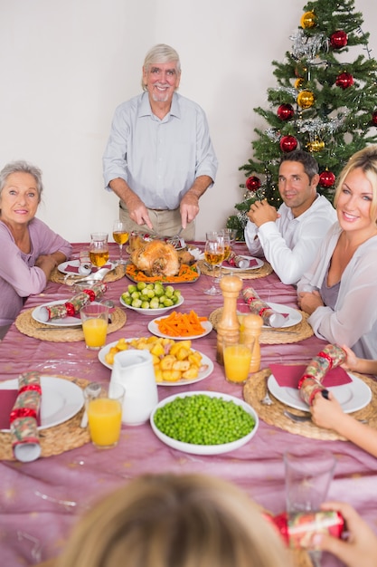 クリスマスの七面鳥を彫っている幸せな祖父