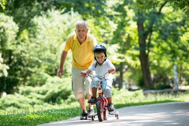 幸せな祖父と子供は楽しい時を過し、美しい晴れた日に公園で遊ぶ