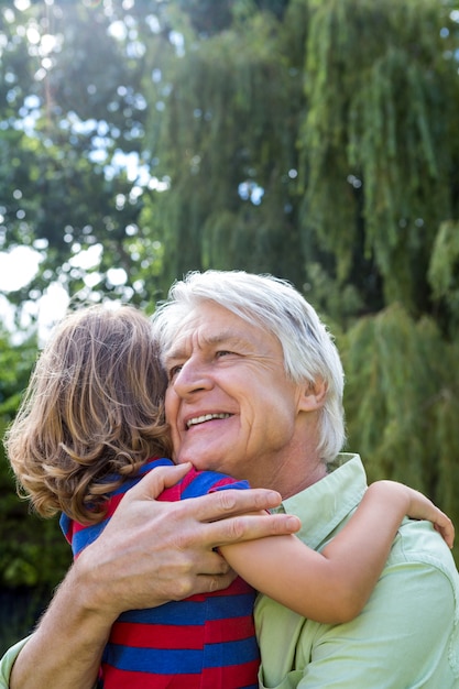 Happy grandfather hugging grandson at yard