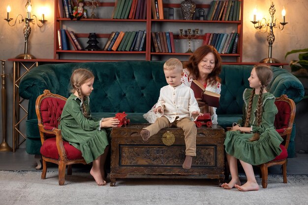 Happy grandma and grandchildren reading book together and having fun at home