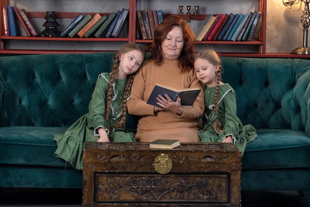 Happy grandma and grandchildren reading book together at home