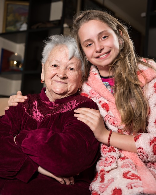 Photo happy grandmother and granddaughter posing at home