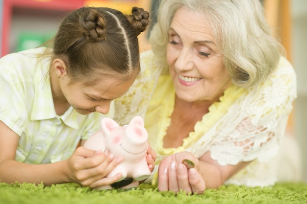 Happy grandmother and granddaughter with piggy bank