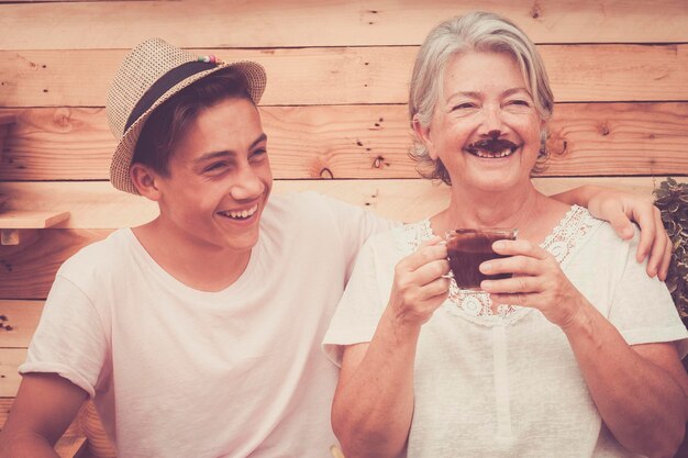 Happy grandmother and grandson standing against wooden wall