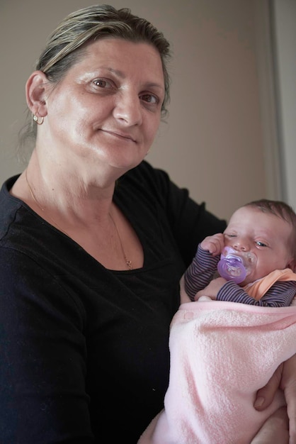 Photo happy grandmother holding newborn baby at home