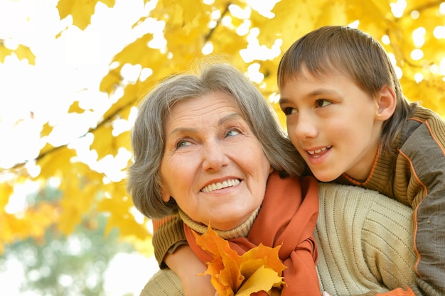 Happy grandmother with boy resting in the autumn park