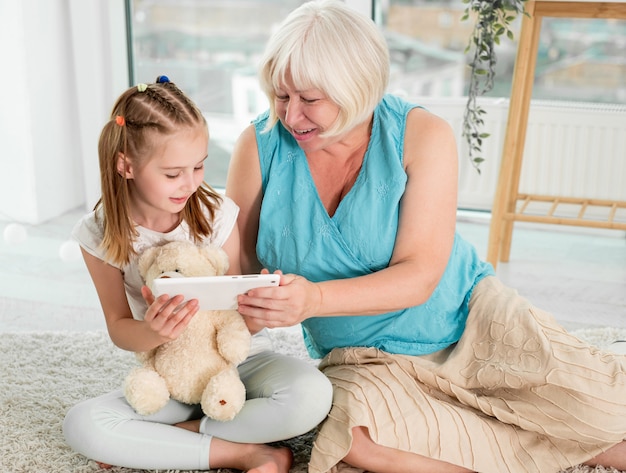 Happy grandmother with granddaughter using tablet