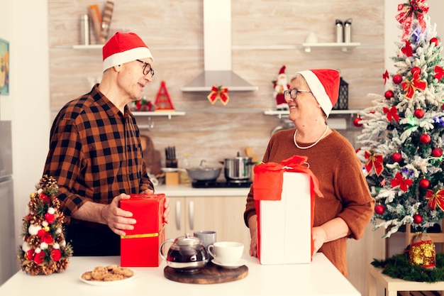 Happy grandparents celebrating christmas exchanging\
presents