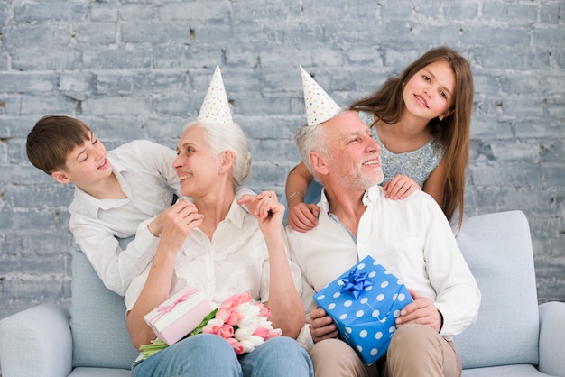 Happy grandparents looking at their grandchildren enjoying birthday party