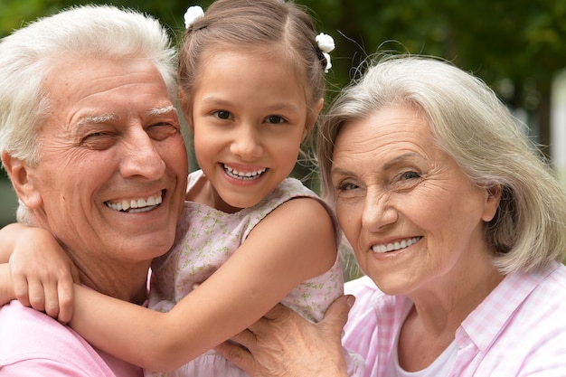 Happy grandparents with granddaughter in summer park