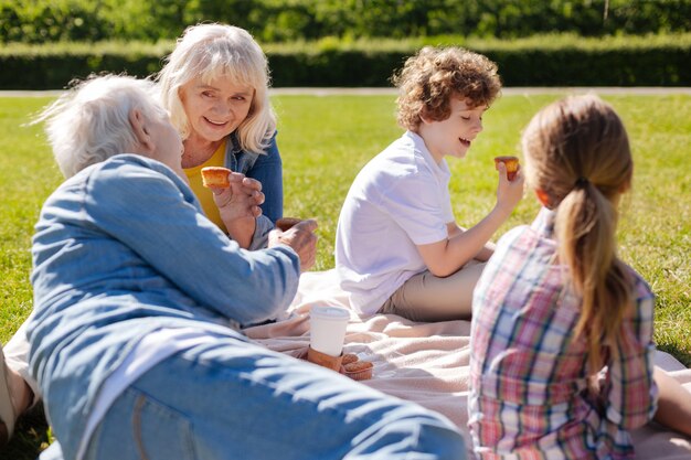 Nonna felice che tiene i dolci nella mano sinistra mentre si alimenta e guarda il marito