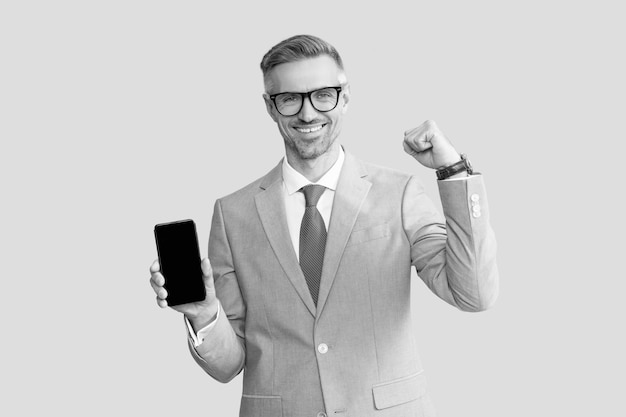 양복과 안경 새 앱에서 전화 화면을 보여주는 행복한 회색 남자