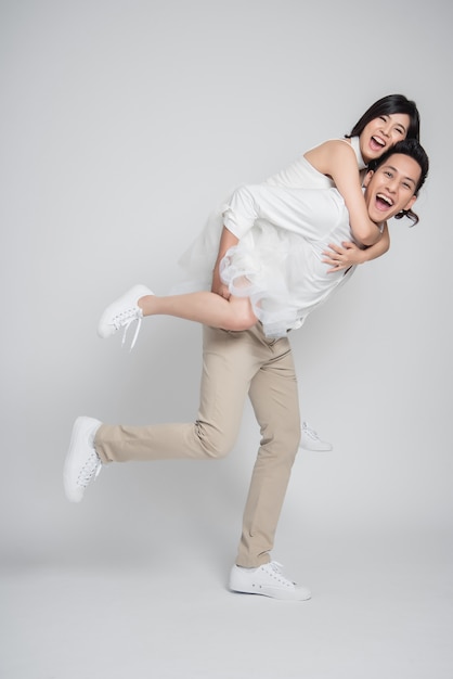 Happy groom gives a bride piggyback ride