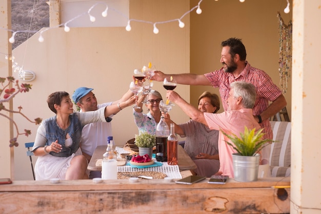 Felice gruppo di persone di età diverse che celebrano e si divertono insieme in amicizia a casa o al ristorante