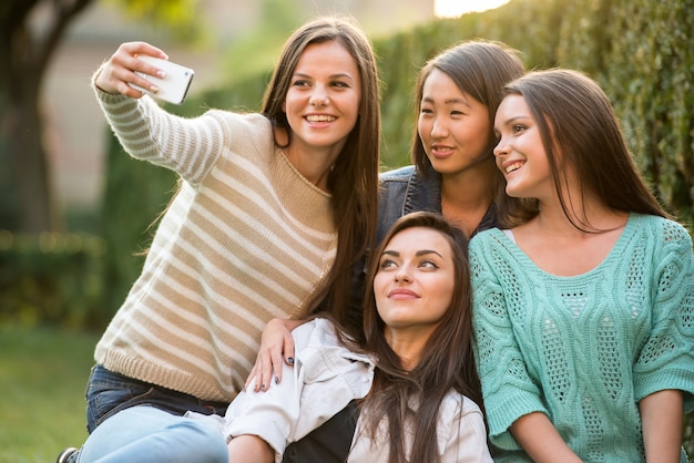 Felice gruppo di studentesse sono seduti al parco.