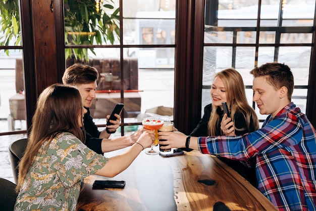 ビール醸造所バーレストランでビールやカクテルを飲み、チリンチリンと鳴らす友人の幸せなグループ男女が一緒に楽しんでいる飲料ライフスタイルコンセプト