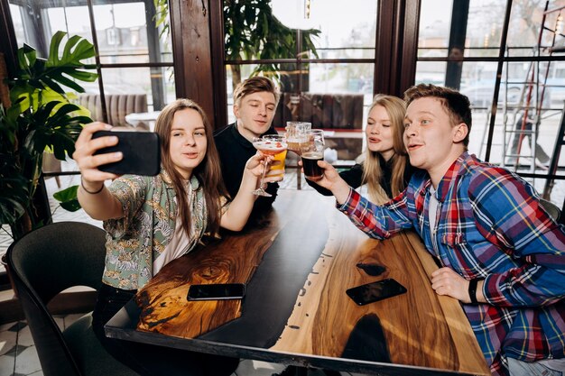 Happy group of friends drinking and clinking with beer and cocktails at brewery bar restaurant