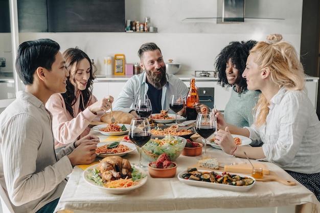 Happy group of friends having dinner party at home Cheerful young people having lunch break together