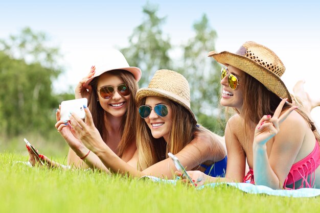 happy group of friends lying on the grass and taking selfie