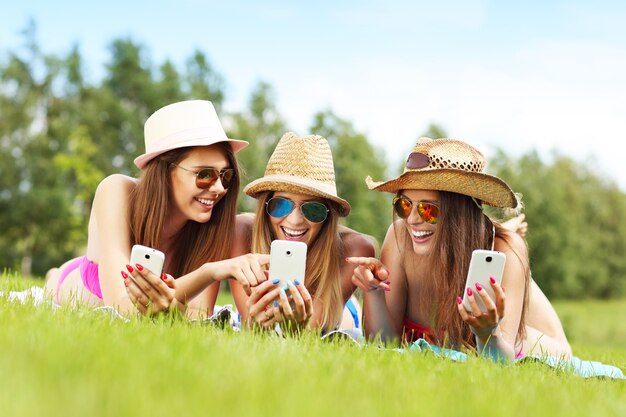 happy group of friends lying on the grass and texting