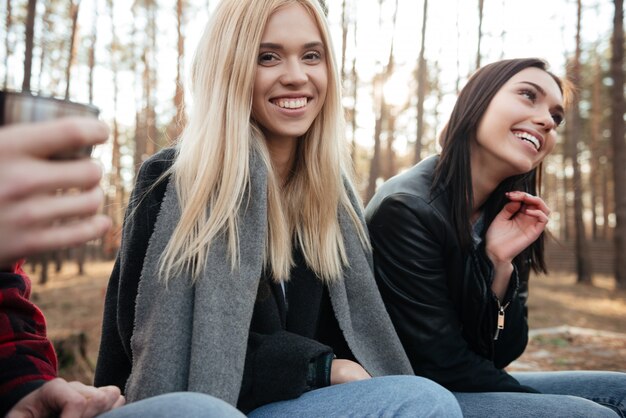 Photo happy group of friends sitting outdoors in the forest.