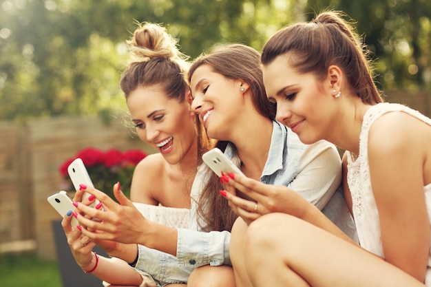 happy group of friends with smartphones sitting outdoors