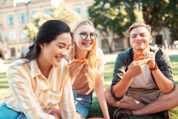 Happy groupmates eating pizza in the university yarn