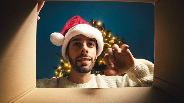 Happy guy opens and looks inside a christmas box