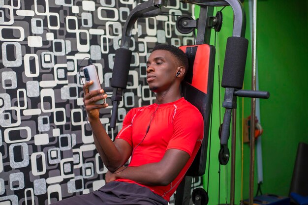 Happy guy using his phone in gym during break