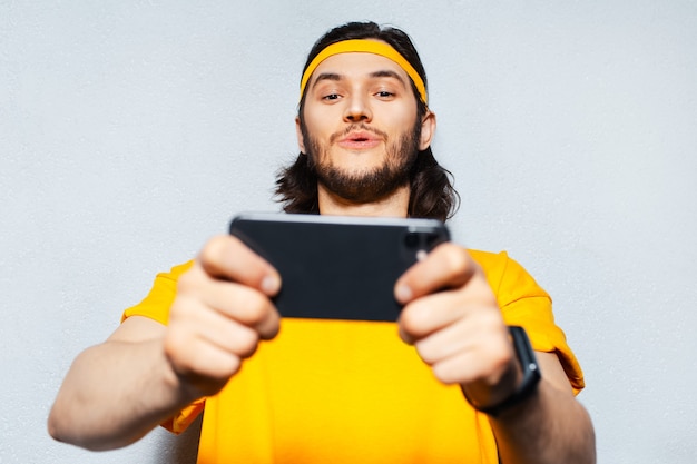 Photo happy guy using smartphone on grey background.