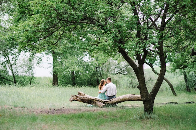 Happy guy in a white shirt and a woman in a turquoise dress walking in the forest park