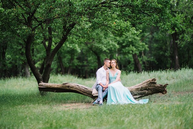 Happy guy in a white shirt and a woman in a turquoise dress walking in the forest park