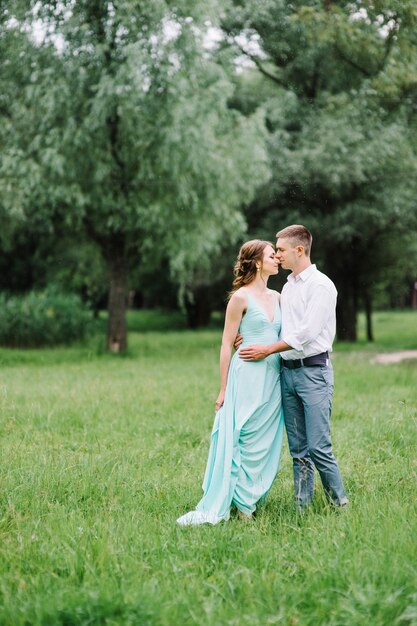 Happy guy in a white shirt and a woman in a turquoise dress walking in the forest park