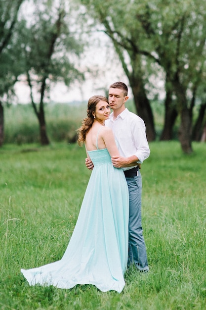 Happy guy in a white shirt and a woman in a turquoise dress walking in the forest park