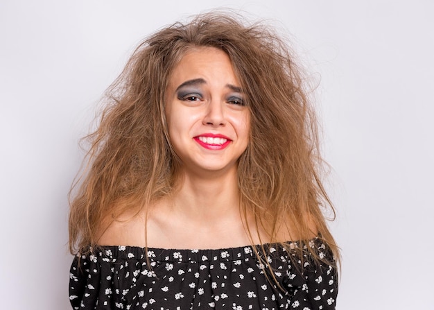 Photo happy halloween concept cheerful teen girl with crazy hairstyle and spooking makeup on gray background surprised caucasian young teenager looking at camera in amazement