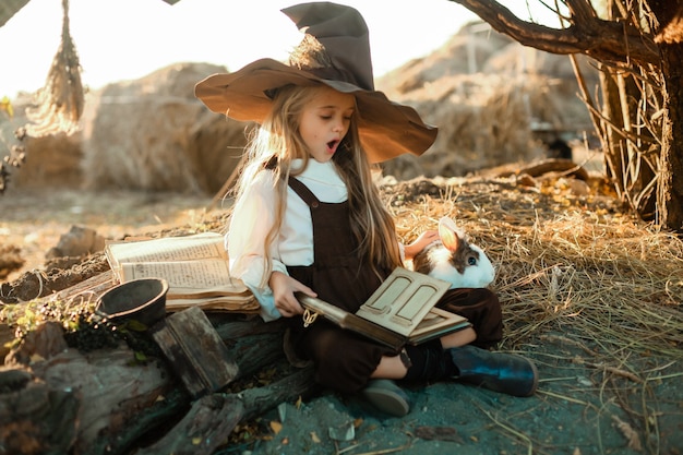 Счастливого Хэллоуина. Милая девушка в костюме ведьмы находится в логове ведьмы. Милая веселая маленькая ведьма варит волшебное зелье. Хэллоуин.