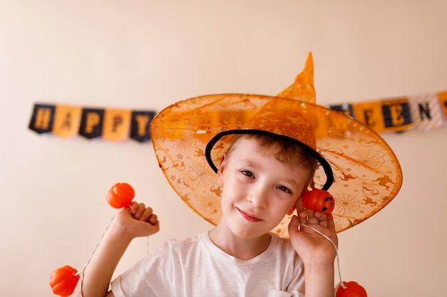 Happy Halloween! Cute little wizard with a pumpkin on beige background.