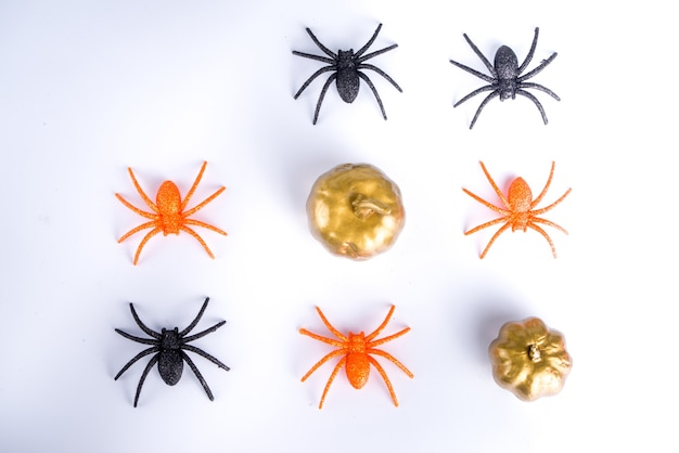 Happy Halloween day holiday background. Flat lay with sweets and decorations for kids party, bucket pack with spiders, candy sweets, bat, on white table copy space top view frame