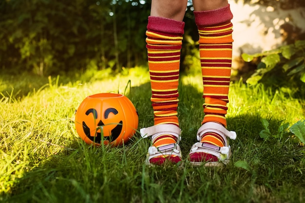 Счастливый день Хэллоуина Маленький ребенок стоит на траве в костюме ведьмы рядом с тыквой Джека
