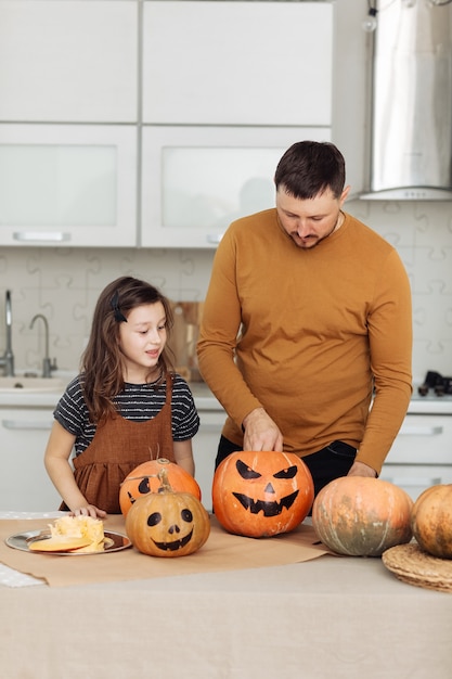 Felice halloween. padre e figlia piccola intagliano una zucca. la famiglia felice si sta preparando per halloween.