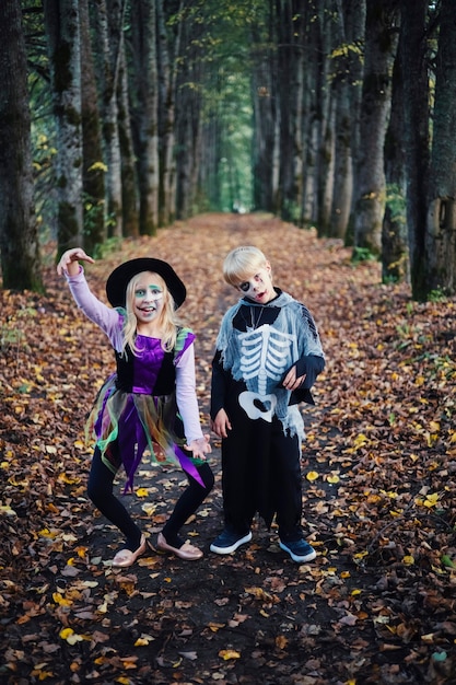 Счастливого Хэллоуина. Забавные дети, брат и сестра, развлекаются в карнавальных костюмах в помещении.