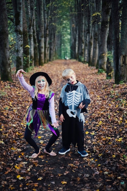 Happy Halloween. Funny kids brother and sister have fun in carnival costumes indoors.