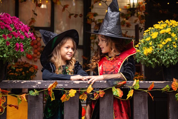 happy Halloween girls in witch costumes have fun in the fall near the house