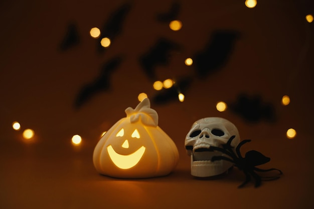 Happy Halloween Glowing pumpkin skull spider on dark orange background with lights and bats